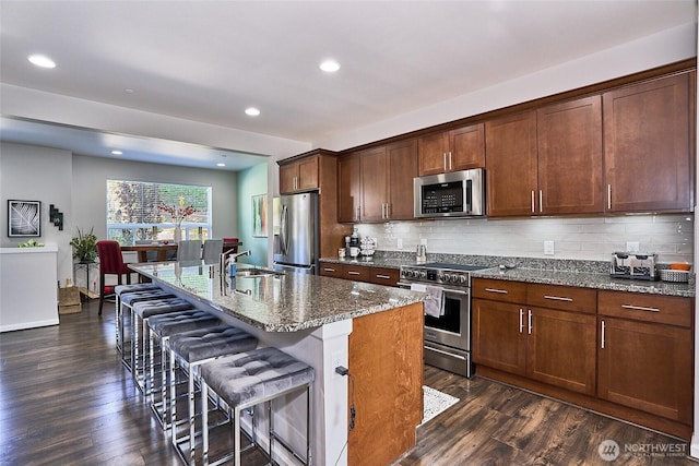 13146 83rd Ln S, Seattle, WA 98178 - kitchen with appliances with stainless steel finishes, a breakfast bar, a sink, a kitchen island with sink, and dark wood finished floors