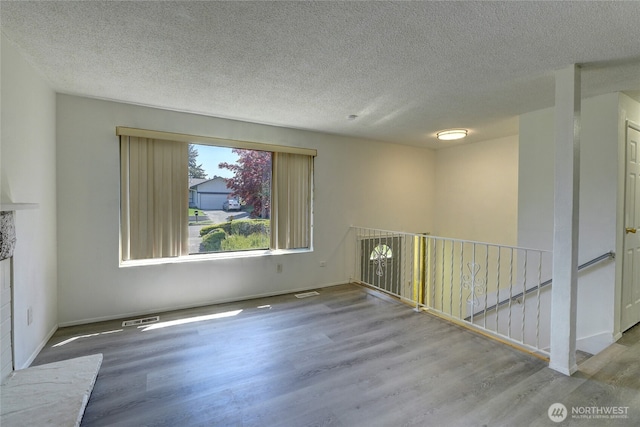 1917 E 60th St, Tacoma, WA 98404 - spare room with a textured ceiling, baseboards, wood finished floors, and visible vents