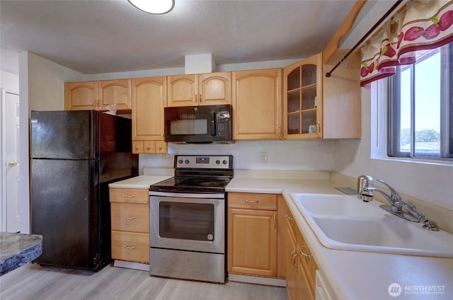 1917 E 60th St, Tacoma, WA 98404 - kitchen with a sink, light wood finished floors, light countertops, glass insert cabinets, and black appliances