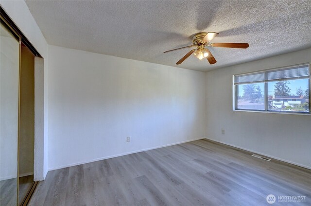 1917 E 60th St, Tacoma, WA 98404 - unfurnished room featuring ceiling fan, a textured ceiling, baseboards, wood finished floors, and visible vents