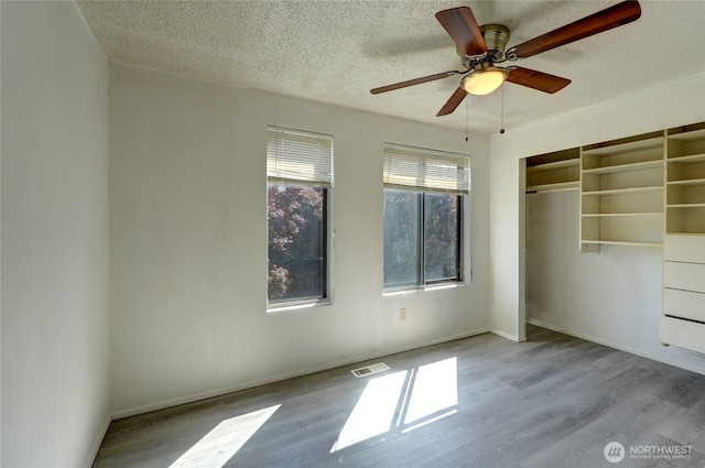 1917 E 60th St, Tacoma, WA 98404 - unfurnished bedroom with a textured ceiling, a ceiling fan, wood finished floors, visible vents, and a closet