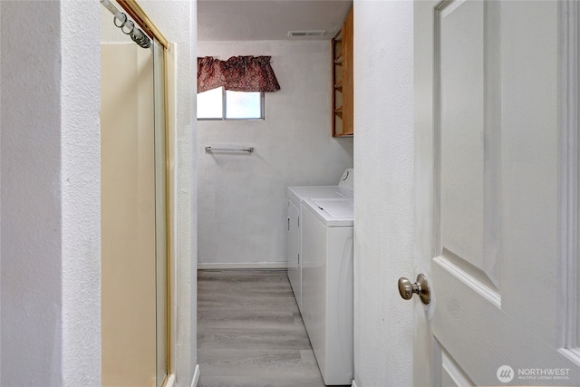 1917 E 60th St, Tacoma, WA 98404 - laundry area featuring visible vents, cabinet space, independent washer and dryer, and light wood finished floors