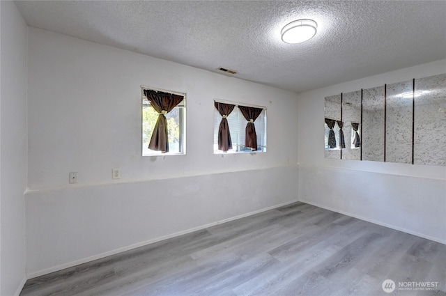 1917 E 60th St, Tacoma, WA 98404 - unfurnished room with baseboards, a textured ceiling, visible vents, and wood finished floors