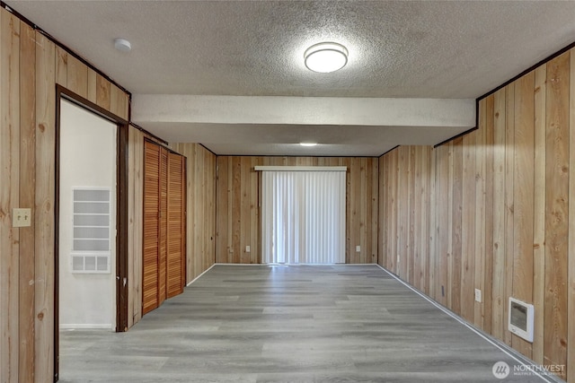 1917 E 60th St, Tacoma, WA 98404 - spare room featuring light wood-type flooring, wood walls, and a textured ceiling