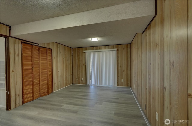 1917 E 60th St, Tacoma, WA 98404 - unfurnished bedroom featuring a textured ceiling, wood walls, wood finished floors, and a closet