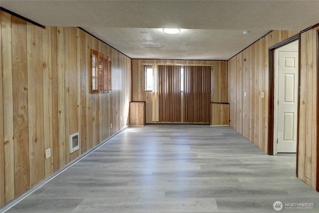 1917 E 60th St, Tacoma, WA 98404 - empty room featuring wood finished floors, wood walls, a textured ceiling, and visible vents