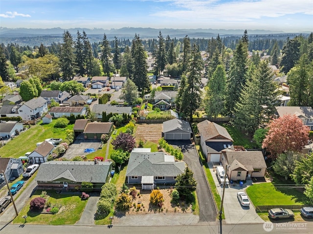 aerial view of residential area featuring a mountain backdrop and a heavily wooded area