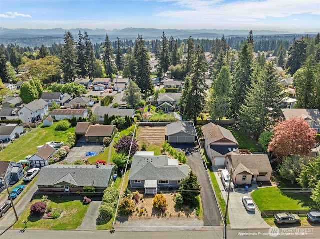 aerial perspective of suburban area featuring a mountain backdrop and a forest