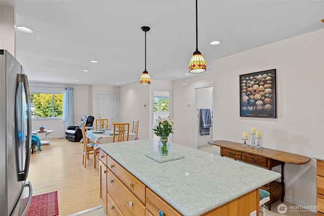 kitchen featuring freestanding refrigerator, baseboards, recessed lighting, light wood-style floors, and a kitchen island