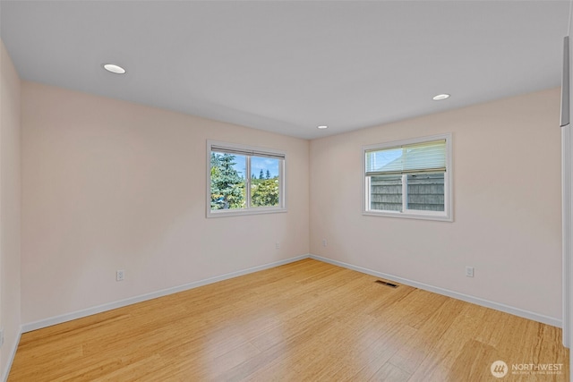spare room featuring light wood-type flooring, baseboards, and recessed lighting