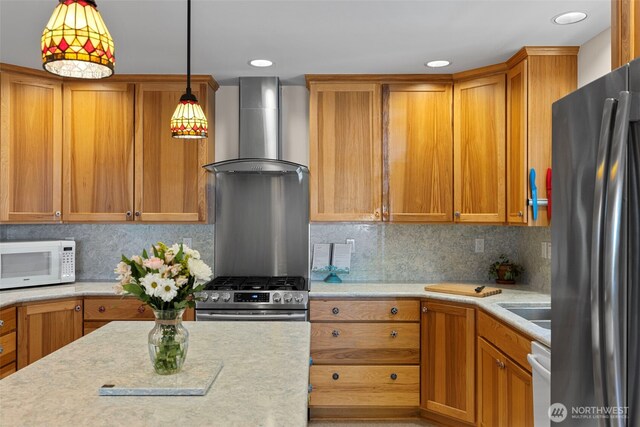 kitchen featuring appliances with stainless steel finishes, wall chimney range hood, light countertops, decorative light fixtures, and recessed lighting