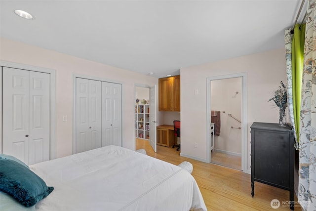 bedroom featuring two closets, light wood-style flooring, and connected bathroom