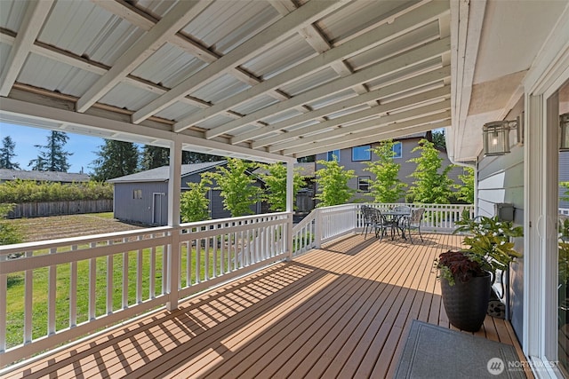 wooden deck with outdoor dining space and an outbuilding