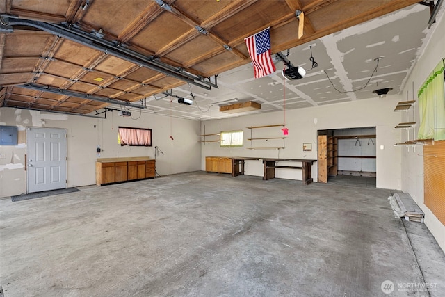 garage with electric panel, a garage door opener, and a workshop area