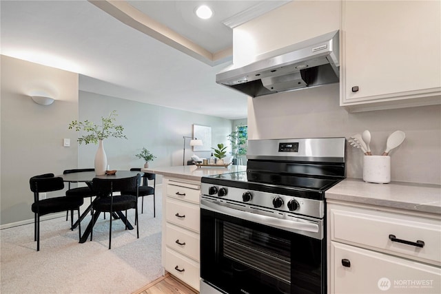 912 3rd Ave W Unit 303, Seattle, WA 98119 - kitchen with white cabinetry, wall chimney range hood, light countertops, and stainless steel electric stove