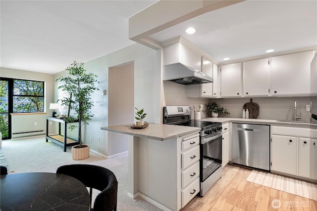 912 3rd Ave W Unit 303, Seattle, WA 98119 - kitchen featuring a baseboard heating unit, a sink, a peninsula, light countertops, and appliances with stainless steel finishes