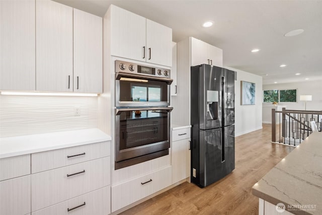 6409 NW 202nd Cir, Ridgefield, WA 98642 - kitchen featuring fridge with ice dispenser, stainless steel double oven, light wood-type flooring, light stone countertops, and recessed lighting