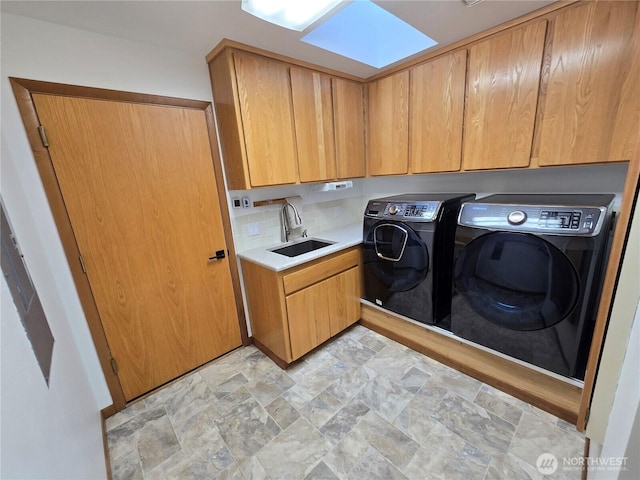 clothes washing area with a sink, cabinet space, stone finish floor, and washing machine and clothes dryer