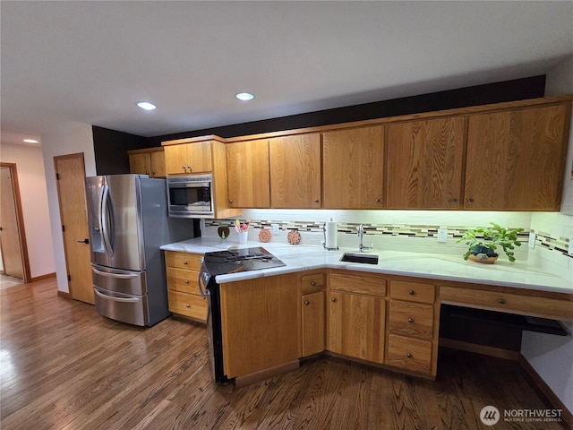 kitchen featuring dark wood-style floors, light countertops, a sink, backsplash, and stainless steel appliances