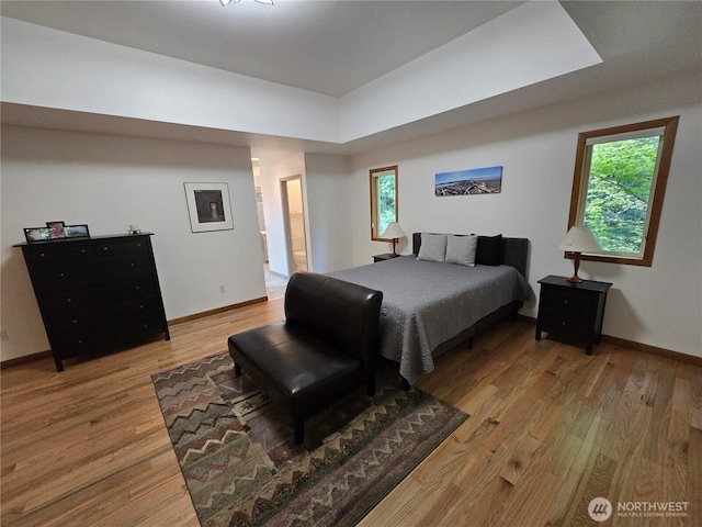 bedroom with baseboards, multiple windows, and light wood-style flooring