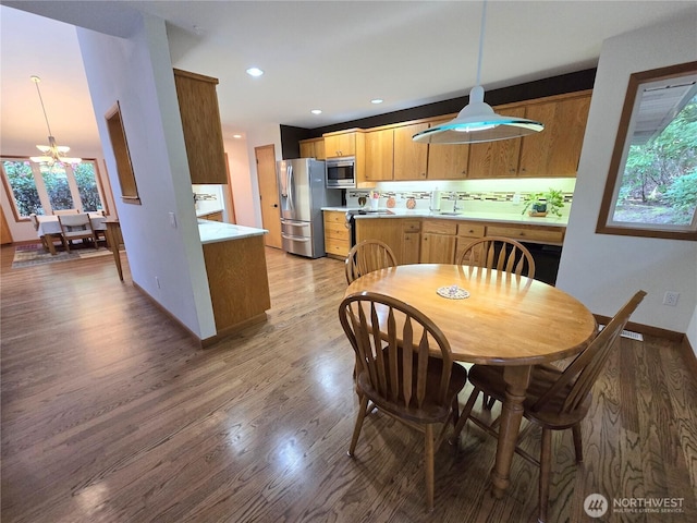 dining space with light wood-style floors, baseboards, a healthy amount of sunlight, and an inviting chandelier