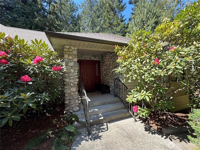 property entrance featuring a shingled roof and stone siding