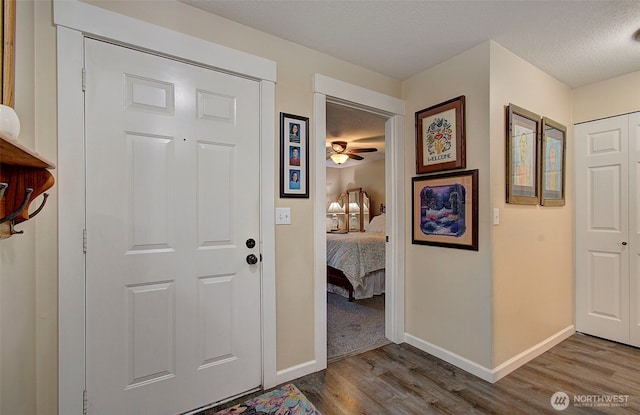 entrance foyer with baseboards, a textured ceiling, ceiling fan, and wood finished floors