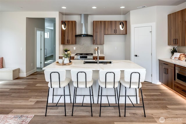 21403 39th Dr SE Unit B, Bothell, WA 98021 - kitchen with wall chimney exhaust hood, a sink, a kitchen bar, stainless steel appliances, and light wood finished floors
