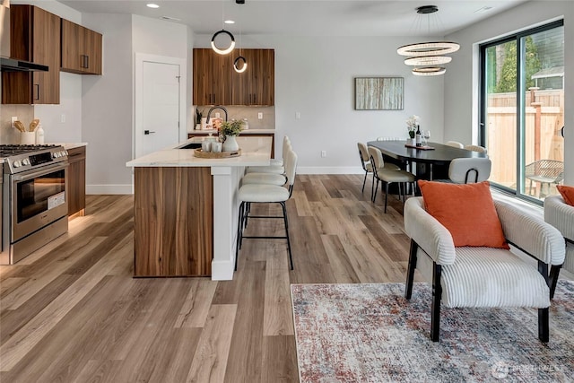 21403 39th Dr SE Unit B, Bothell, WA 98021 - kitchen featuring stainless steel gas range, wall chimney range hood, a sink, light countertops, and baseboards