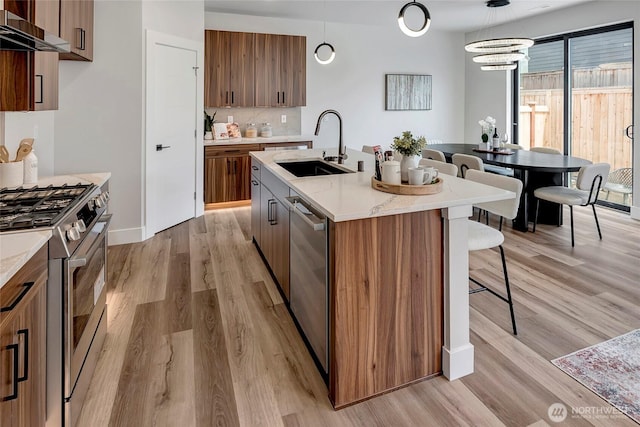 21403 39th Dr SE Unit B, Bothell, WA 98021 - kitchen featuring a sink, wall chimney exhaust hood, appliances with stainless steel finishes, a kitchen breakfast bar, and light wood-type flooring