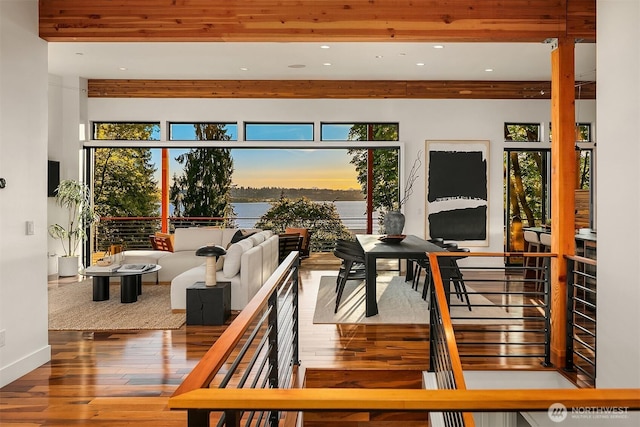 sunroom / solarium featuring beam ceiling, a water view, and a healthy amount of sunlight