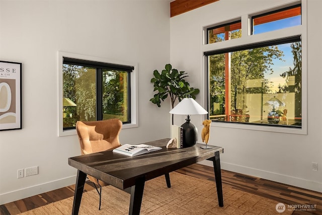 office featuring visible vents, wood finished floors, baseboards, and a healthy amount of sunlight