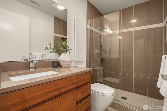 bathroom with a stall shower, toilet, vanity, and visible vents