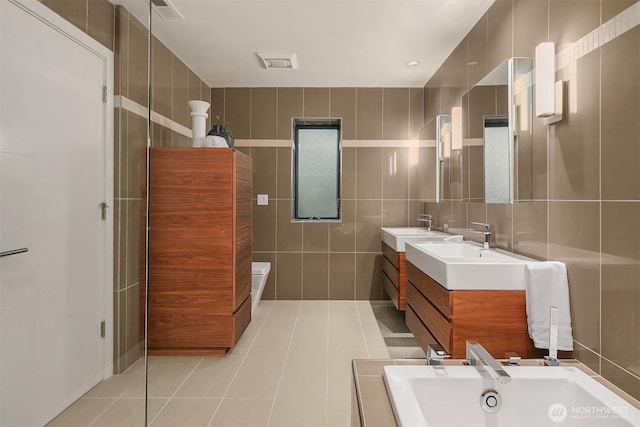 full bath with double vanity, tile walls, tile patterned flooring, and a bath