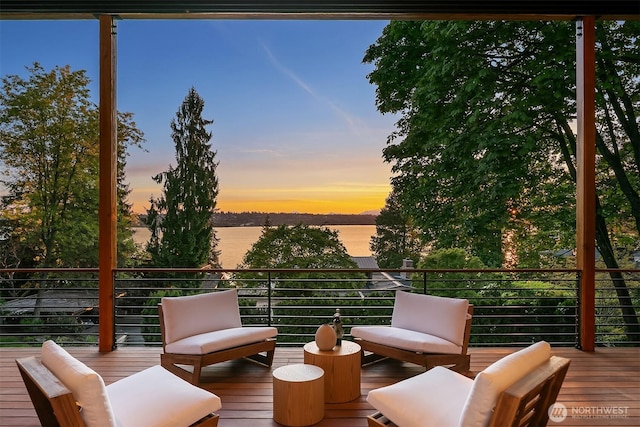 deck at dusk featuring a water view