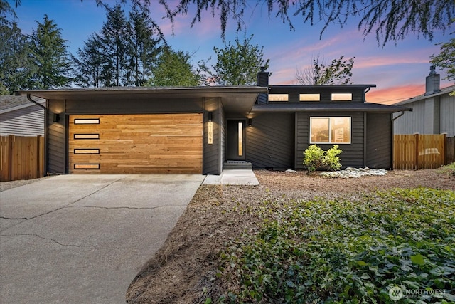 view of front of home featuring a garage, fence, a chimney, and concrete driveway