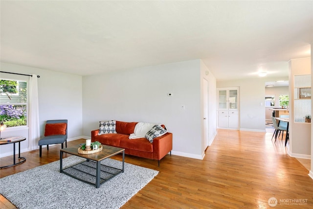 living area featuring light wood-style floors, baseboards, and a wealth of natural light
