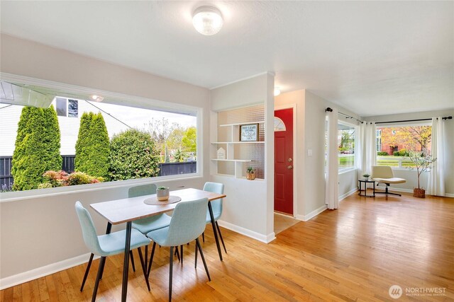 dining space with baseboards and light wood-style flooring