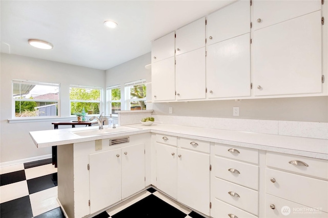 kitchen with light countertops, tile patterned floors, white cabinetry, and a sink