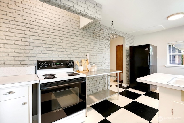 kitchen featuring freestanding refrigerator, electric range, light countertops, white cabinetry, and tile patterned floors