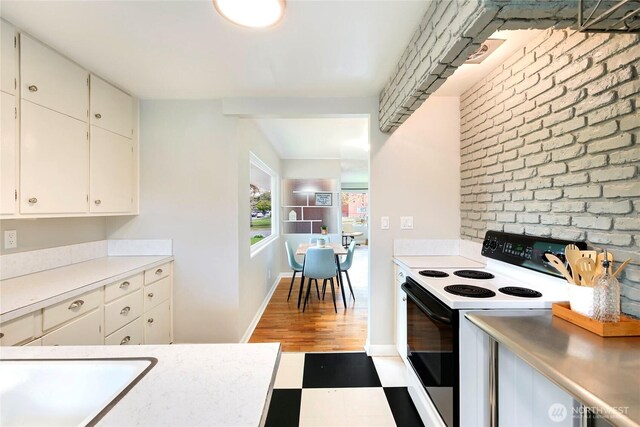 kitchen featuring wood finished floors, light countertops, baseboards, electric stove, and white cabinetry