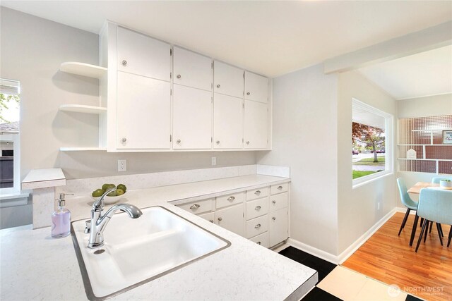 kitchen with white cabinets, open shelves, plenty of natural light, and a sink