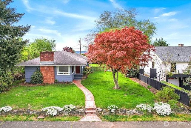 view of front facade with fence, a chimney, a shingled roof, and a front lawn