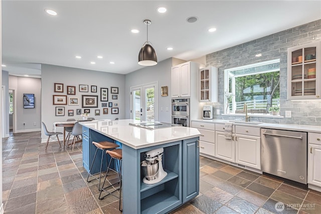 kitchen with appliances with stainless steel finishes, open shelves, white cabinetry, a sink, and a kitchen island