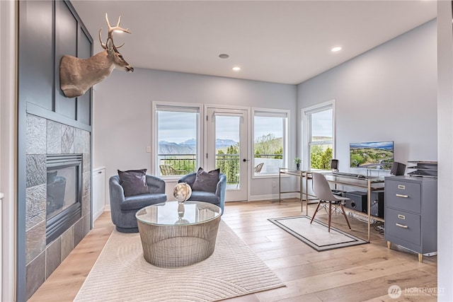 office featuring healthy amount of natural light, a tiled fireplace, light wood-style flooring, recessed lighting, and baseboards