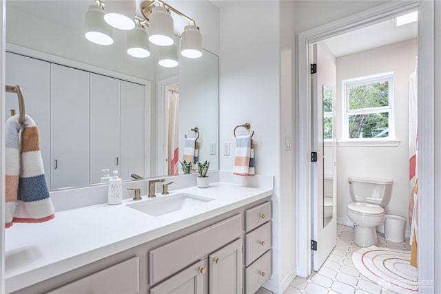 bathroom with vanity, toilet, baseboards, and a chandelier