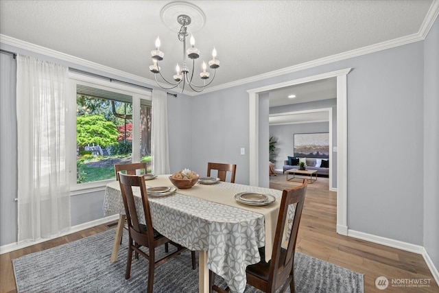 dining room with a chandelier, crown molding, baseboards, wood finished floors, and a textured ceiling