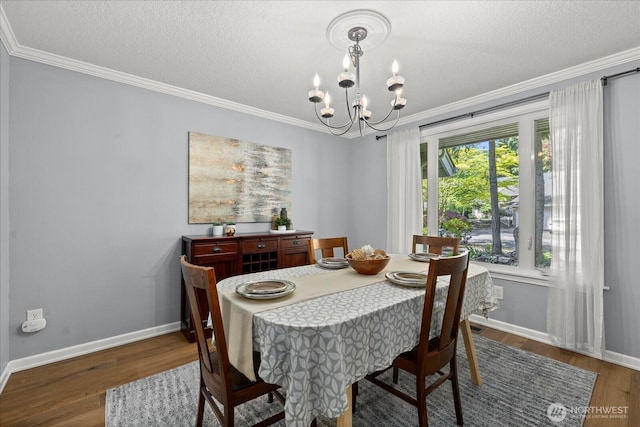 dining area featuring a chandelier, ornamental molding, baseboards, wood finished floors, and a textured ceiling