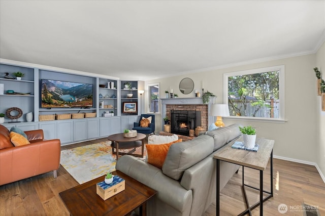living room with wood finished floors, a brick fireplace, ornamental molding, baseboards, and built in shelves