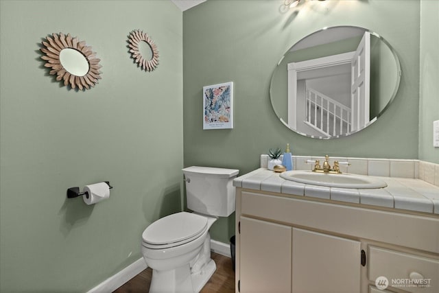 bathroom with toilet, baseboards, wood finished floors, and vanity